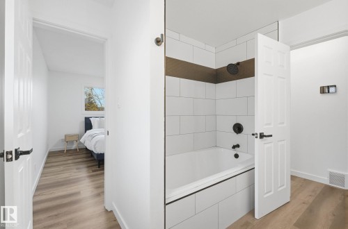 Full bath with light wood-type flooring, double sink vanity, and tiled shower/ tub. - 2722 104A Street, Edmonton, AB 