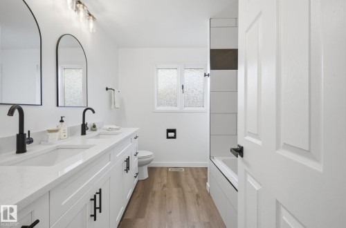 Full bath with light wood-type flooring, double sink vanity, and tiled shower/ tub. - 2722 104A Street, Edmonton, AB 