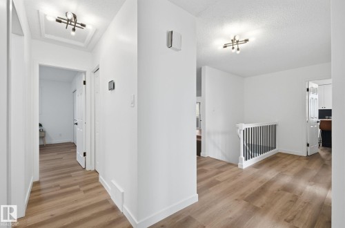 Corridor featuring an upstairs landing and stair leading to the fully finished basement. - 2722 104A Street, Edmonton, AB 
