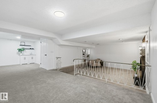 Spare room featuring carpet, textured ceiling, recessed lighting, two levels and a black brick fire place. - 2722 104A Street, Edmonton, AB 