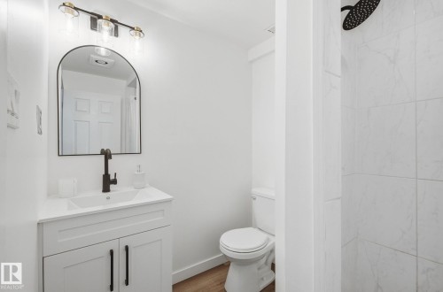 Full bathroom featuring vanity with quartz counter tops, a shower, and wood finished floors - 2722 104A Street, Edmonton, AB 