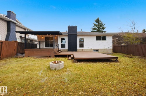 Rear view of property featuring an outdoor fire pit, a fenced backyard, a deck, and a chimney - 2722 104A Street, Edmonton, AB 