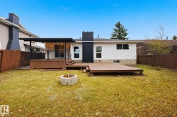 Rear view of property featuring an outdoor fire pit, a fenced backyard, a deck, and a chimney - 