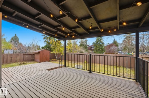 Two layered large deck with metal railing and partially cover by a build in gazebo, facing a fenced backyard and a storage shed. - 2722 104A Street, Edmonton, AB 