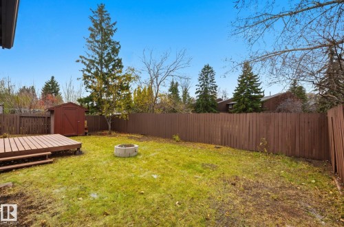 Fenced backyard featuring a storage unit, an outdoor fire pit, and a deck - 2722 104A Street, Edmonton, AB 