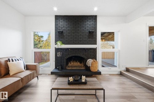 Living room with wood finished floors, a brick fireplace, and recessed lighting - 2722 104A Street, Edmonton, AB 