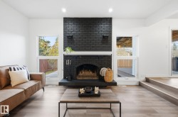 Living room with wood finished floors, a brick fireplace, and recessed lighting - 