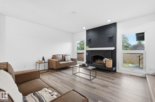 Living area featuring two large windows allowing plenty of natural light, a fireplace, light wood-style floors, and recessed lighting - 2722 104A Street, Edmonton, AB 
