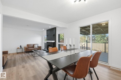 Dining space with a fireplace, light wood-style flooring, and a textured ceiling - 2722 104A Street, Edmonton, AB 