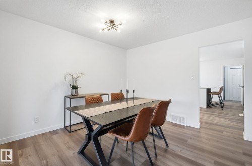 Dining room with wood finished floors, upgraded lighting fixture and a textured ceiling - 2722 104A Street, Edmonton, AB 