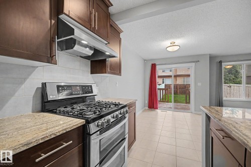 Kitchen featuring stainless steel appliances, wood-finish cabinetry, granite countertops, and a subway tile backsplash - 16810 53 Street, Edmonton, AB 