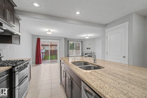 Kitchen island with an undermount double-basin sink, polished chrome faucet, and granite countertop - 16810 53 Street, Edmonton, AB 