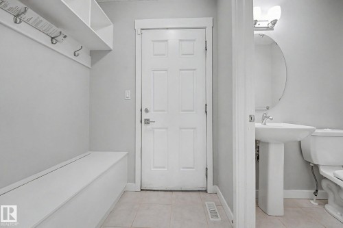 Entryway featuring built-in bench storage, upper shelving with coat hooks, and light-toned tile flooring - 16810 53 Street, Edmonton, AB 