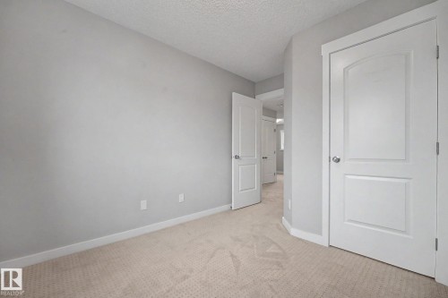Carpeted room with light gray walls, white baseboards, and a textured ceiling - 16810 53 Street, Edmonton, AB 