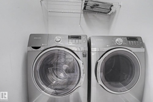Dedicated laundry area featuring a front-loading washer and dryer set, overhead wire shelving, and neutral wall finishes - 16810 53 Street, Edmonton, AB 
