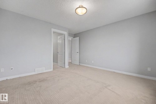 Spacious room featuring neutral carpeting, light gray walls, white trim, and a flush-mount ceiling light fixture - 16810 53 Street, Edmonton, AB 