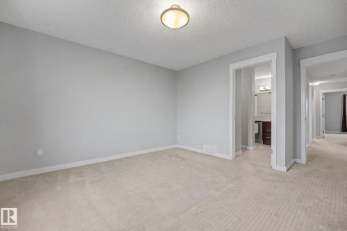 Carpeted interior room featuring light gray walls and white baseboards - 16810 53 Street, Edmonton, AB 
