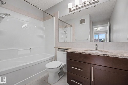 Bathroom featuring a full vanity with a granite-style countertop, undermount sink, and dark wood-finish cabinetry - 16810 53 Street, Edmonton, AB 