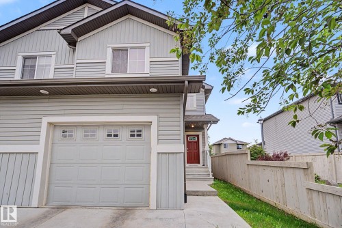 Light gray siding exterior with a dark brown shingled roof, featuring a single-car garage with transom windows - 16810 53 Street, Edmonton, AB 