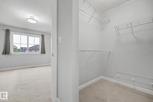Walk-in closet featuring white wire shelving and a neutral carpet floor - 16810 53 Street, Edmonton, AB 