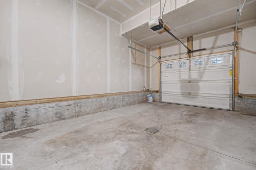 Spacious garage featuring a concrete floor, framed walls, and an overhead door with upper window panels - 16810 53 Street, Edmonton, AB 