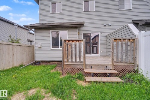 Rear exterior with wood deck, sliding glass patio door, and light gray siding - 16810 53 Street, Edmonton, AB 