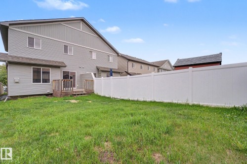 Rear exterior featuring light gray siding, multiple windows, and a wood deck with railings - 16810 53 Street, Edmonton, AB 