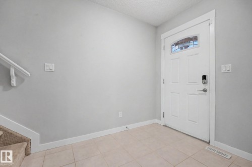 Entryway featuring a white paneled door with an arched decorative glass insert and a smart lock - 16810 53 Street, Edmonton, AB 