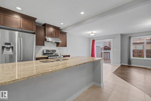 Modern kitchen featuring a breakfast bar with stone countertops - 16810 53 Street, Edmonton, AB 