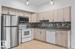 Kitchen featuring wood-finish cabinetry, stainless steel refrigerator and microwave, white electric range, and a multi-toned tile backsplash - 