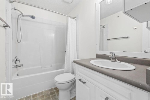 Bathroom featuring a white vanity with a gray countertop, an undermount sink, and a mirrored medicine cabinet - 116 6315 135 Avenue, Edmonton, AB 