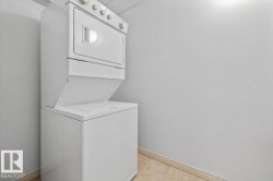 Integrated white stackable laundry unit set against light gray walls with beige flooring - 