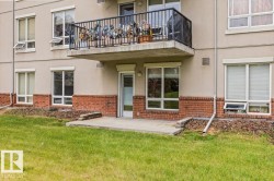 Ground-level patio with direct exterior access, surrounded by a manicured lawn - 