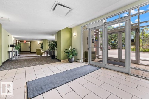 Spacious entryway featuring a combination of light-toned tile flooring and carpet, a wall of glass doors, and recessed lighting - 116 6315 135 Avenue, Edmonton, AB 
