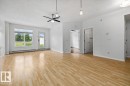 Spacious living area featuring light wood-finish flooring, white walls, and a textured ceiling - 116 6315 135 Avenue, Edmonton, AB 