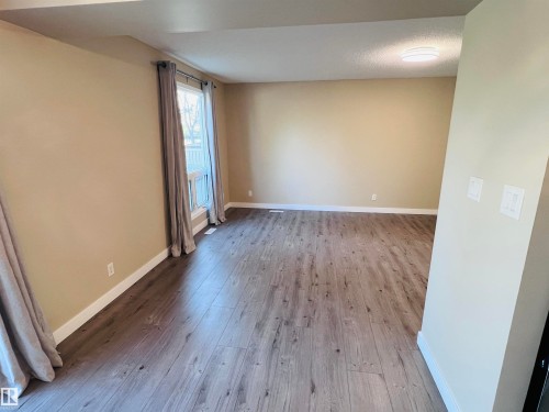 Spacious interior room featuring wood-finish flooring, neutral wall tones, and a large window - 2544 79 Street, Edmonton, AB - Indoor Photo Showing Other Room