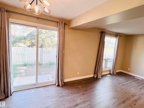 Spacious interior featuring wood-finish flooring, neutral paint tones, and a contemporary chandelier - 2544 79 Street, Edmonton, AB - Indoor Photo Showing Other Room