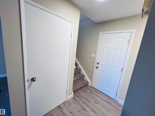 Entryway featuring wood-finish flooring, a paneled door with black hardware, and a closet with a white door - 2544 79 Street, Edmonton, AB - Indoor Photo Showing Other Room