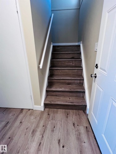 Wood-finish flooring throughout, complemented by a staircase featuring matching wood-finish treads and white risers - 2544 79 Street, Edmonton, AB - Indoor Photo Showing Other Room
