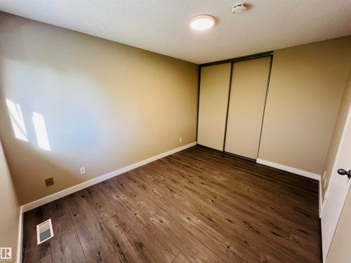 Room featuring wood-finish flooring, neutral wall tones, white baseboards, and a flush-mount ceiling light - 2544 79 Street, Edmonton, AB - Indoor Photo Showing Other Room