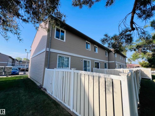 Exterior featuring tan siding with white trim, multiple windows, and sliding glass doors - 2544 79 Street, Edmonton, AB - Outdoor With Exterior