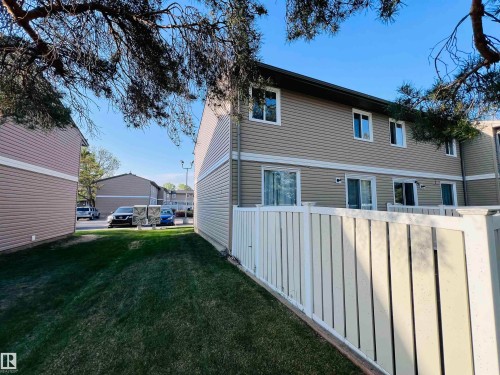 Fenced patio area with direct exterior access, tan siding, multiple windows, and a manicured lawn - 2544 79 Street, Edmonton, AB - Outdoor