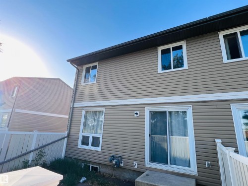Rear exterior showcasing beige horizontal siding, white trim, and a dark brown fascia - 2544 79 Street, Edmonton, AB - Outdoor With Exterior