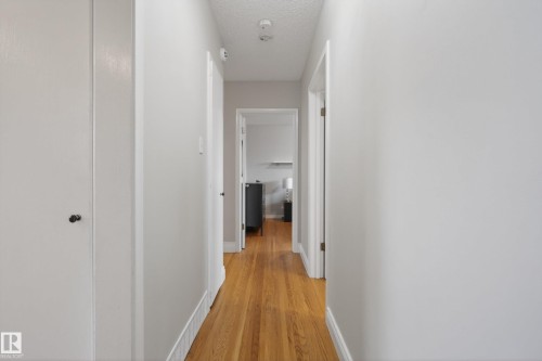 Hallway with wood-finish flooring, light gray wall paint, white trim, and white doors - 16105 109A Avenue, Edmonton, AB 