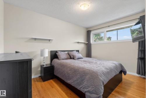 Bedroom featuring hardwood flooring, neutral wall tones, a large window, and ceiling-mounted lighting - 16105 109A Avenue, Edmonton, AB 