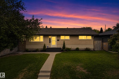 Exterior featuring a concrete walkway, established lawn, mature landscaping, and a front entry with a storm door - 16105 109A Avenue, Edmonton, AB 