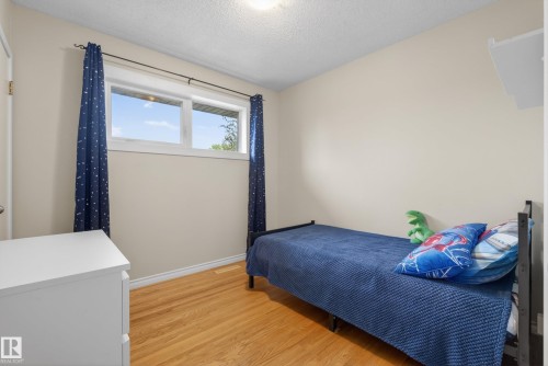 Room featuring wood-finish flooring, a double window with white trim, and light beige wall paint - 16105 109A Avenue, Edmonton, AB 