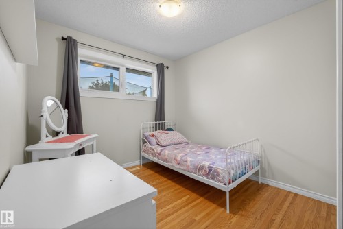 Room featuring hard surface flooring, white baseboards, and a window with dark drapery - 16105 109A Avenue, Edmonton, AB 