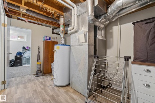 Basement utility area featuring wood-finish flooring, exposed ceiling joists, and a hot water heater - 16105 109A Avenue, Edmonton, AB 