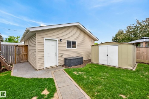 Rear exterior featuring beige siding, a white door, and a built-in window - 16105 109A Avenue, Edmonton, AB 